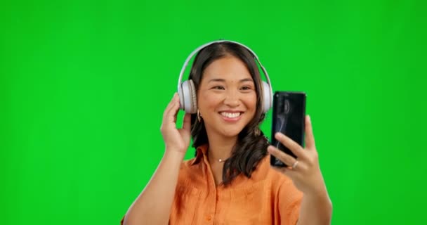 背景のモックアップ空間に隔離されたスタジオの緑の画面上の音楽のヘッドフォン 自撮りや女性 ソーシャルメディアで写真やアジア人を撮る プロフィール写真やインフルエンサーの幸せな記憶 — ストック動画