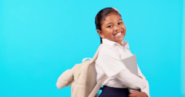 スタジオブルーの背景に隔離された教育や宿題に興奮している女の子の学校 本や肖像画 子供や子供の笑顔で統一された保持の教科書で幸せ — ストック動画