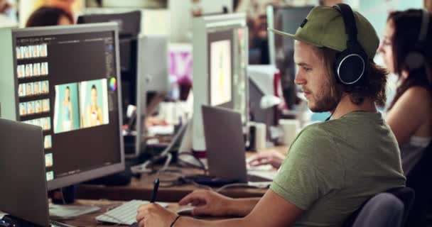 写真デザイン オフィスでヘッドフォンを扱う男のコンピュータソフトウェア フォトエディターの仕事 創造的なコンテンツスタートアップとオンラインウェブサイトのための技術雑誌レイアウトを計画従業員 — ストック動画