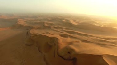 İnsansız hava aracı, çöl veya kum ve güneş batımı için Dubai 'de gökyüzü, safaride doğa güzelliği, manzara veya Afrika sahara. Tepe, toprak ya da özgürlük Suudi Arabistan 'da, çorak arazide ya da yaz gündoğumunda sabah güneşinde.