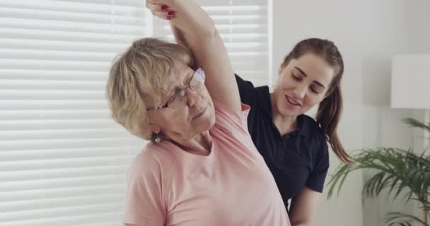 老年病人 理疗师和伸展手臂 用于康复和理疗 为治疗 健康和健康而配备脊医的老年妇女 包括体能训练和保健 — 图库视频影像