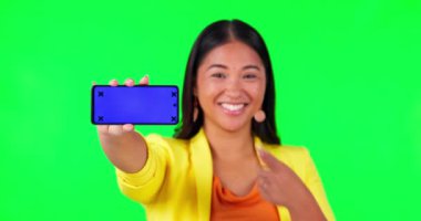 Yeşil ekran, kadın yüzü ve el, stüdyo arka planında takip işaretleri olan telefon modeline işaret ediyor. Portre, mekan ve Asyalı kadın haberler için ürün yerleştirme gösteriyor..