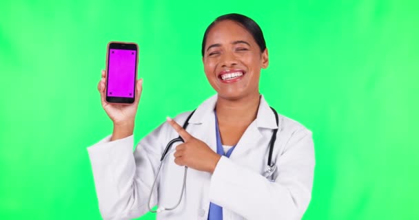 女性は 医療サービス 連絡先やテレヘルスで緑色の画面を指しています 追跡マーカーとスタジオの背景を持つモバイルアプリのモックアップ上の医療看護師やラテン人の顔 — ストック動画