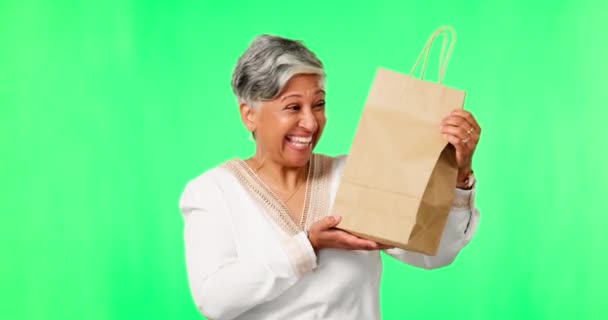パッケージ お祝いとスタジオの背景に対して茶色の袋で興奮して顔 緑の画面とシニア女性 肖像画 女性の人と小包 贈り物と幸福と成熟したモデル — ストック動画