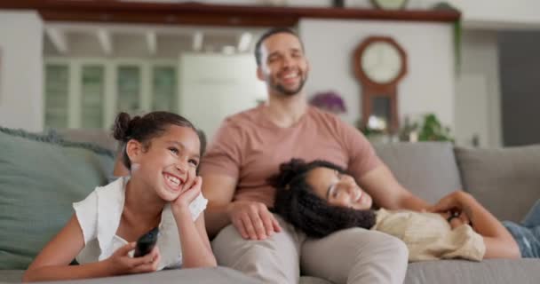快乐的家庭 在沙发上看电视 在他们的家在周末欢笑 亲热和嬉闹 娱乐和父母带着女童在客厅里带着爱 微笑或流口水 — 图库视频影像