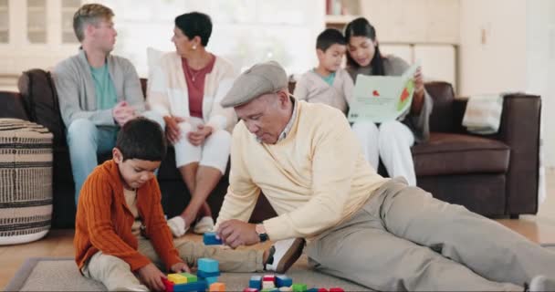 建物のブロックと祖父は訪問中に自宅のリビングルームで孫と遊んでいます 床の上に彼の男の子孫との絆で高齢者の男と子供 愛やおもちゃ — ストック動画