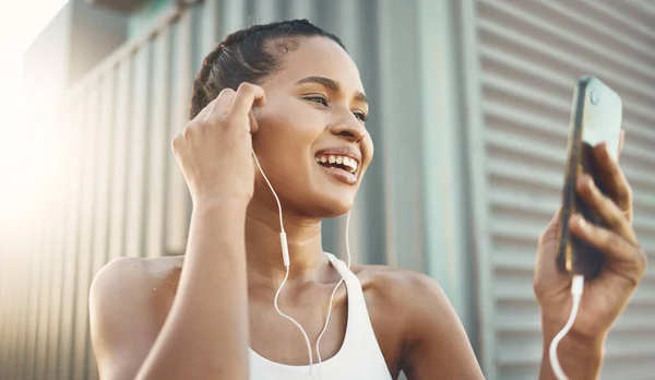 Fitness, woman with smartphone and listening to music for motivation with lens flare. Happy or health wellness, workout or exercise and female athlete listen to podcast in sportswear for resilience.