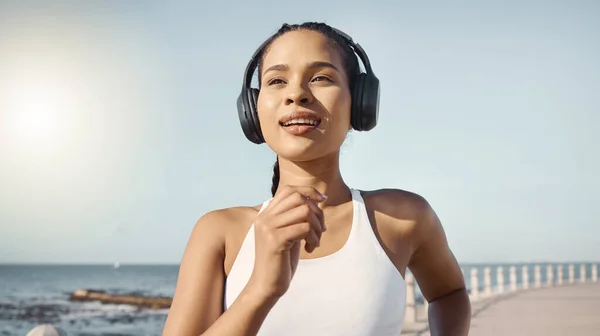 女人和带着耳机在海边跑步 进行健康 有声和阳光的锻炼 听音乐 夏天在海上锻炼 早上锻炼有氧运动或健康的身体 — 图库照片