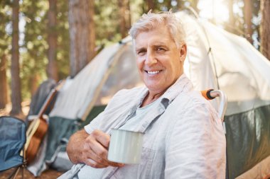 Kamp, sabah ve tatilde kahveyle yaşlı bir adamın portresi ya da ormanda tatil macerası. Gülümse, mutlu ve yaşlı insan ya da kampçı. Bir çadırın yanında dinlen. Emekliliğin tadını çıkar..