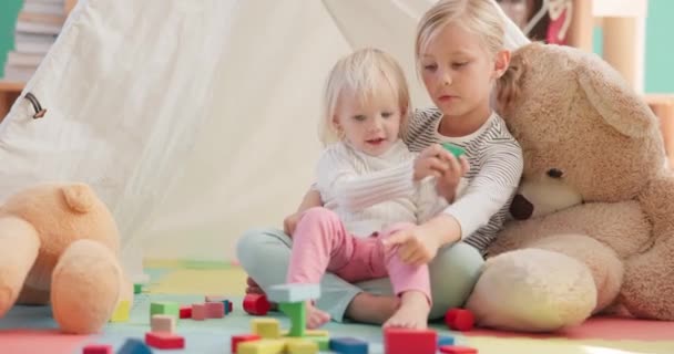 家庭で一緒に子供たち おもちゃや接着剤 愛とプレイルームで姉妹のためのゲームをプレイ 床の上の赤ちゃんとのサポート 関係開発と女の子の子供 教育とブロックパズルで学ぶ — ストック動画