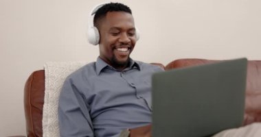 Kulaklıklar, dizüstü bilgisayarlar ve iş için evden müzik akışı, rahatlama ve akıl sağlığı olan bir adam. Mutlu profesyonel, girişimci ya da Afrikalı kişi bilgisayar ve oturma odasında ses dinliyor..