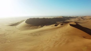 Kum, günbatımı ve çölün insansız hava aracıyla özgürlük, macera ve keşif için seyahat. Açık alan, manzara ve gündoğumu barışı için Namibya kumulları çevresindeki ışık ile yaz, doğa ve ufuk..