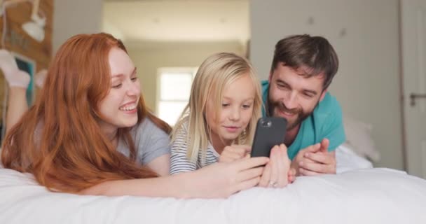 流口水 家里有电话在床上玩游戏 社交媒体或迷因 父母和一个女孩一起在家里卧室的手机应用程序上聊天 — 图库视频影像