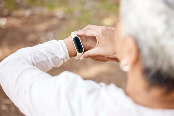 stock image Senior woman, check smart watch and fitness in park to monitor speed, heart or progress. Outdoor, female runner and iot clock for time, training or exercise with stopwatch, nature or summer sunshine.