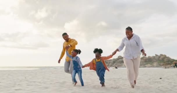 リラックスのためにビーチで黒い家族と一緒に幸せ 旅行と手を携えてください 信頼と自由のために海岸線を歩く親や子供とのサポートと愛 — ストック動画