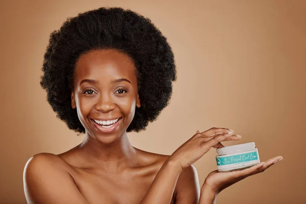 Portrait, hair and keratin product with a black woman in studio on a brown background for cosmetics. Face, smile and haircare treatment in the palm of a happy female model for natural afro hairstyle.