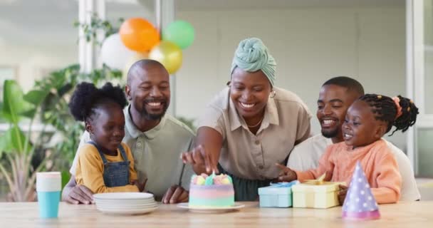 テーブルで両親と祝うために子供のための黒い家族 誕生日ケーキとキャンドル パーティー 品質の時間と愛とケアとの結合や楽しさのために自宅でアフリカの女性 男性と幸せな子供 — ストック動画