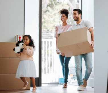 Baba, anne ve kızı yeni evlerinde kutuları olan mutlu ya da heyecanlı bir şekilde hareket ediyorlar. Anne, baba ve çocuk paketli, gülümseyin ya da emlak, emlak ya da aile evinde hayata başlayın.