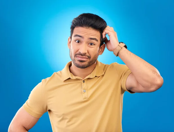 stock image Portrait, head scratch and man confused over question, doubt or uncertain about problem crisis, error or decision. Studio, face and Asian male person unsure about choice isolated on blue background.