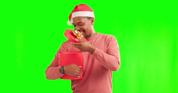 緑の画面とクリスマスの贈り物とお祝いのためのスタジオでサンタクラスの帽子を持つ男 お祝いとクロマキーの背景によってクリスマスプレゼントボックスとアフリカの男性モデルの肖像画 — ストック動画