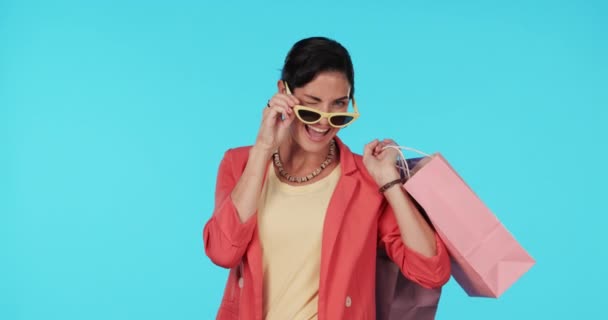 太阳镜 购物袋或快乐女人的脸 穿着蓝色背景的衣服在工作室里 微笑或富有的女孩 有打折或促销的礼物或时尚 — 图库视频影像