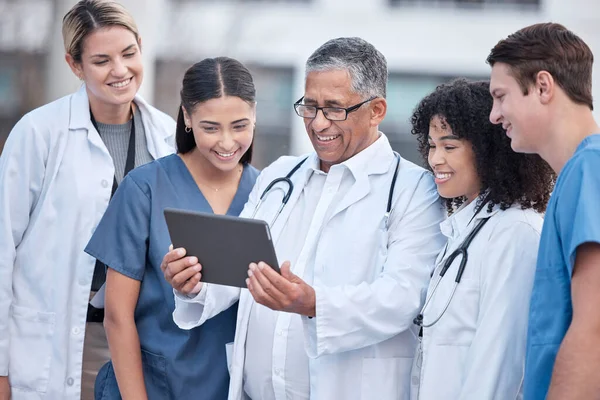 stock image Tablet, doctors and healthcare people at hospital outdoor with clinic management, research and online teamwork. Group, telehealth and medical staff, nurses and mentor with digital technology training.