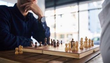 Masa oyunu, satranç ve ofisteki bir masada strateji ya da plan düşünen adamlar. Erkek arkadaşlar birlikte oynamak, gevşemek ve sorun çözme, rekabet veya şah mat için ahşap ikon ile bağ kurmak için.