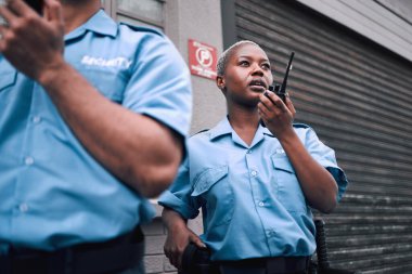Güvenlik, telsiz ve şehirde devriye gezen siyahi bir kadın polis memuru. Şehir merkezindeki bir sokakta kadın gardiyanla telsiz, iletişim ve hizmet..