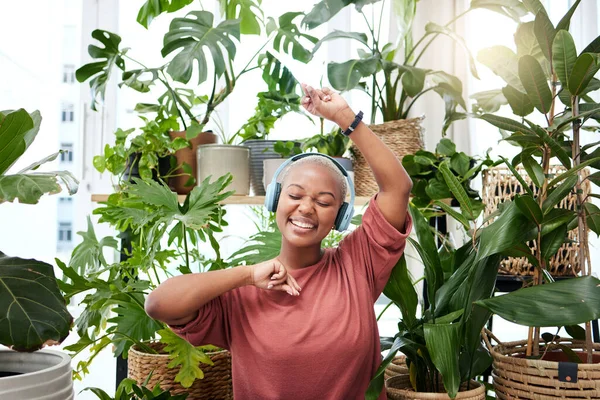 舞蹈和耳机与一个黑人女人在她家旁边的植物 同时流淌音频播放列表 广播和订阅服务 一位快乐的年轻女性紧闭双眼 在一所房子里 — 图库照片