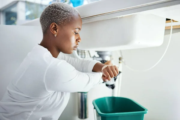 stock image Plumbing, leak and time with a black woman in the bathroom of her home waiting for repair assistance. Sink, emergency and watch with a young female homeowner in her house to stop water using a bucket.