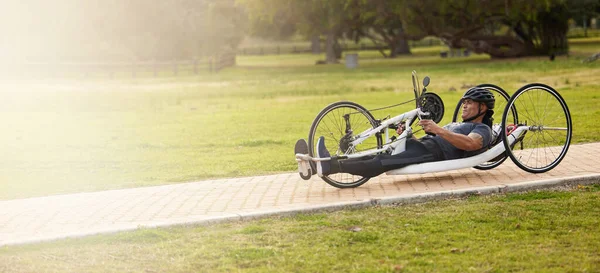 Cycling, fitness and space with man and handcycle in nature for training, sports contest and challenge. Exercise, workout and banner with person with a disability in park for cardio and health mockup.