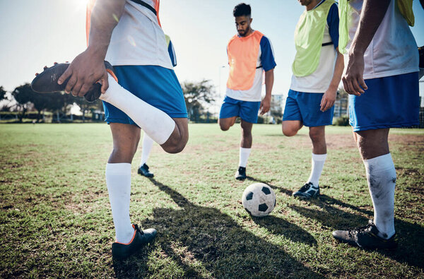 Stretching legs, football player and men training on a field for sports game and fitness. Male soccer team or athlete group together for challenge, workout or exercise outdoor on a grass pitch.