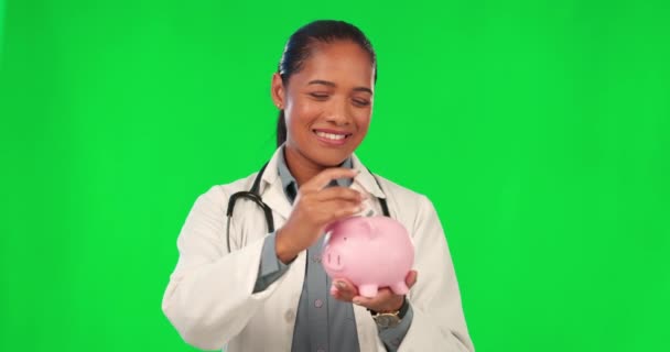 小猪银行 现金和医生在绿色的屏幕上为储蓄 未来的医疗保健计划和医疗保险 为有演播室背景的快乐女性 医学女性和拉丁裔女性存钱 笔记和贷款 — 图库视频影像