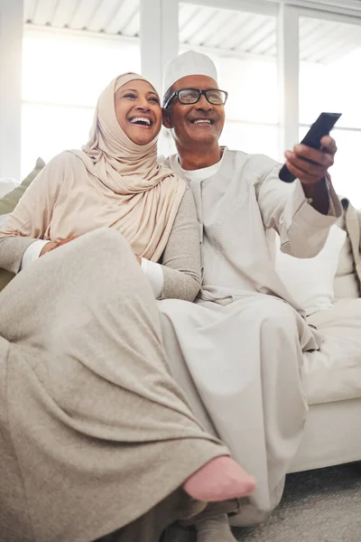 リラックスして イスラム教徒とストリーミング 映画や面白いのためのソファの上に古いカップルとテレビを見て テレビ 幸せな高齢者や女性と一緒に自宅のリビングルームでコメディ 退職とラウンジ — ストック写真