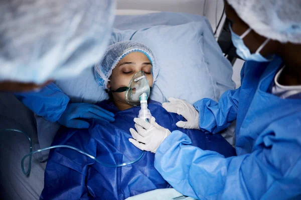 病院のベッドや酸素マスク 呼吸器や医療回復のための操作を持つ女性 緊急時の換気のための呼吸器を備えた医療外科医 麻酔または病気の患者 — ストック写真