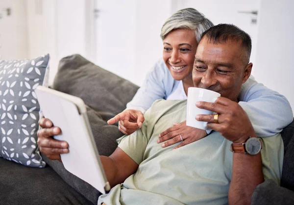 Senior people gadgets in room. Happy elderly couple on sofa in