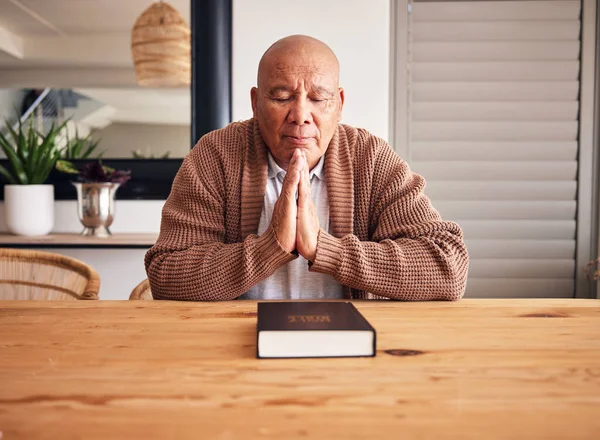 Senior man, bible and praying in home with faith, religion and mindfulness for peace, gratitude and Jesus. Elderly person, eyes closed and worship christian God with spiritual mindset, focus or trust.