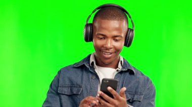 Telefon, müzik kulaklıkları ve arka planda izole edilmiş yeşil ekrandaki siyah adam. Radyo, dinleme ve mutlu Afrikalı kişi müzik listesi, caz podcast veya canlı hip hop müziği eşliğinde dans ediyor.