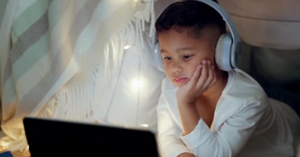 平板电脑 女孩带着耳机 晚上在卧室 家里或网上卡通片 电视节目或听音乐的儿童中播放电影 为小孩或电视在移动应用上看电影或录像 — 图库视频影像