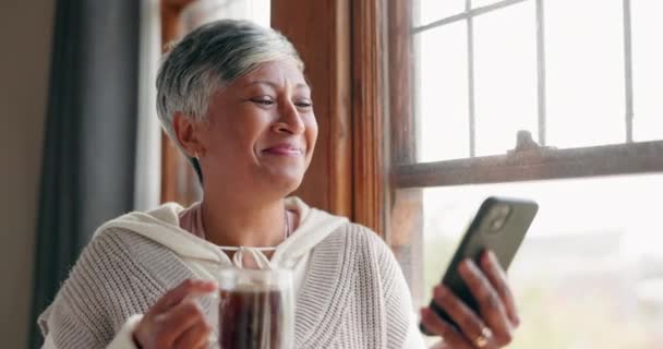 家庭和拿着手机的老年妇女都在家里边喝咖啡边看书 微笑和老年女性在网上的茶点应用中流连忘返地寻找新闻或信息 — 图库视频影像