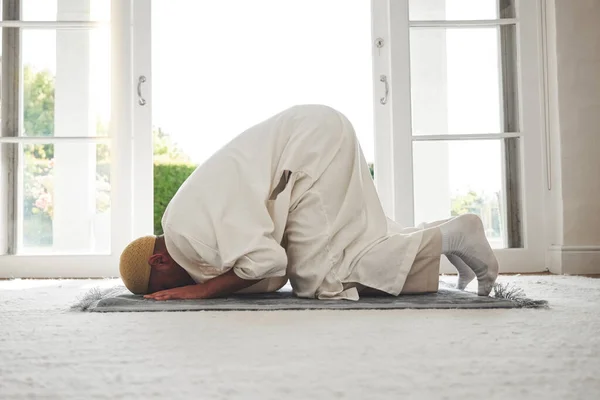 イードムバラク 神と崇拝のためのリビングルームの床に男と祈り イスラム教徒とイスラム教徒 クルアーンと希望とラマダーンと信仰と宗教と感謝のために家でマットで祈る精神的な人 — ストック写真
