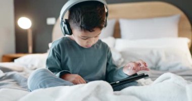 Çocuk, çocuk ve tabletli kulaklıklar yatak odasında online oyunlar, film izlemek ve geceleri eğitim uygulaması oynamak için. Çocuk, dijital teknoloji ve multimedya, müzik ve çizgi film dinlemek.