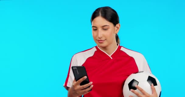 Woman, sports and video call in studio, talk and football celebration, excited and happy by blue background. Girl, professional soccer player and ball with webinar, communication or chat with success.