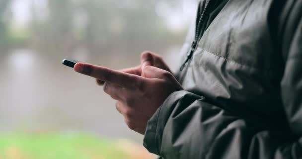 在阴云密布的日子里 在模糊的室外背景下与人的手 电话和交流 冬季在雨中与一个成年人一起输入短信的移动 联系和社交媒体 — 图库视频影像