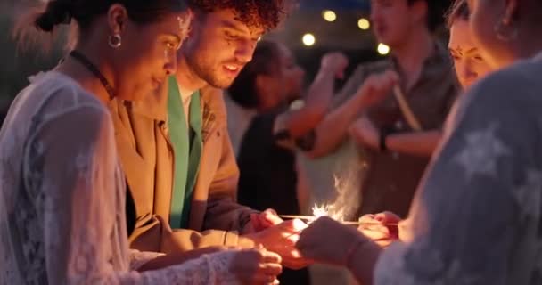 野外の新年イベントでお祝いのためにパーティーで花火 音楽祭の外で幸せな若い男と女性グループの絆で夜 輝きや楽しみ — ストック動画
