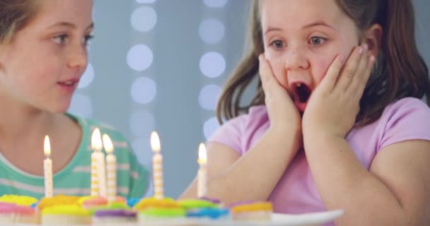 女孩子们 在家里的聚会 活动或庆祝活动中 吹点蜡烛和生日蛋糕作为惊喜 面子或快乐 兴奋的孩子 姐妹或庆祝活动 用甜品杯蛋糕 食物或蜡烛 — 图库视频影像