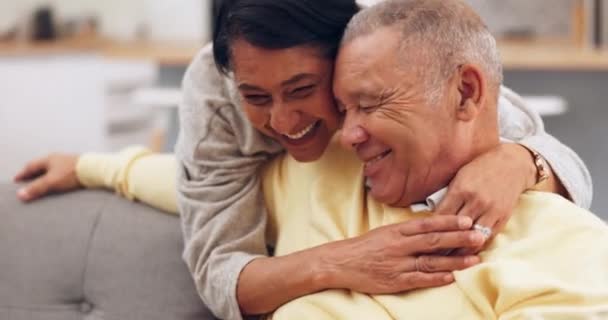 快乐的一对老夫妇 沙发拥抱 牵挂和交谈 在他们的家一起放松和凉爽 在享受退休生活的同时 用有趣的谈话 玩笑或愚蠢的幽默来爱 微笑和老年人 — 图库视频影像