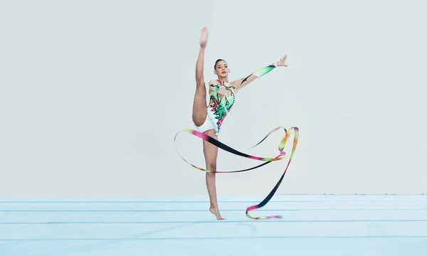 Gymnastics training, woman and ribbon with legs split for competition, sport and balance in portrait. Gymnast, athlete girl or professional dancer for concert, performance and contest with creativity.