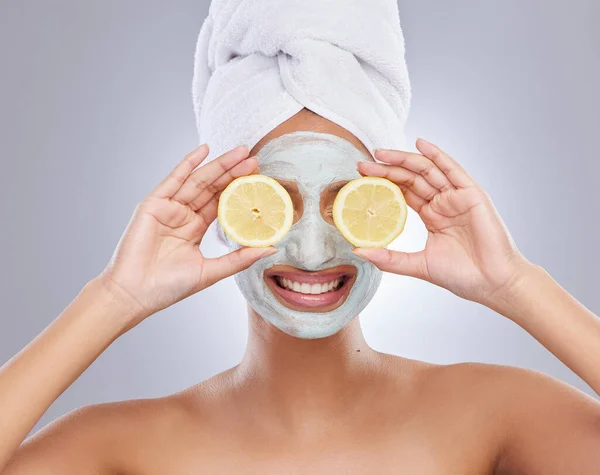 Mask, beauty and lemon with woman in studio for skincare, natural cosmetics and vitamin c. Self care, glow and spa with face of female model and citrus fruit on grey background for detox product.