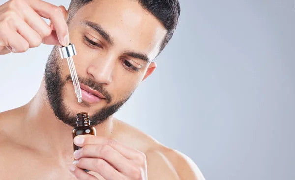 stock image Mockup, serum and man with skincare, cosmetics and dermatology against a grey studio background. Male person, model and guy with oil, beauty and liquid for face, grooming and routine for smooth skin.